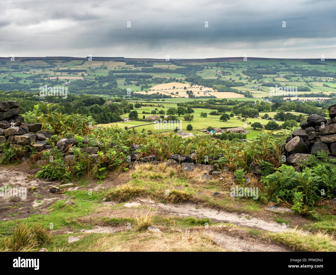Vista su Wharfedale attraverso uno spazio in un secco parete in pietra vicino posto sulla rupe di Burley Moor West Yorkshire Inghilterra Foto Stock