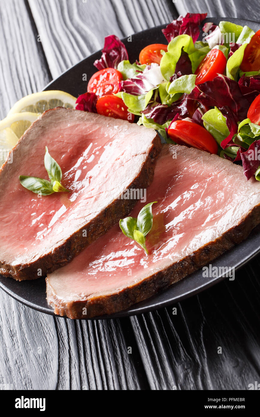Cucinato al momento raro bistecca di manzo con verdura fresca insalata di close-up su una piastra su un piano verticale. Foto Stock