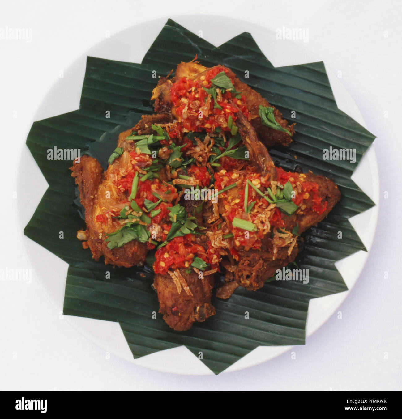 Cucina malese, Ayam panggang; pollo cucinato con aglio e calce, servita con una calda salsa sambal sul grande verde a forma di stella a foglia. Foto Stock