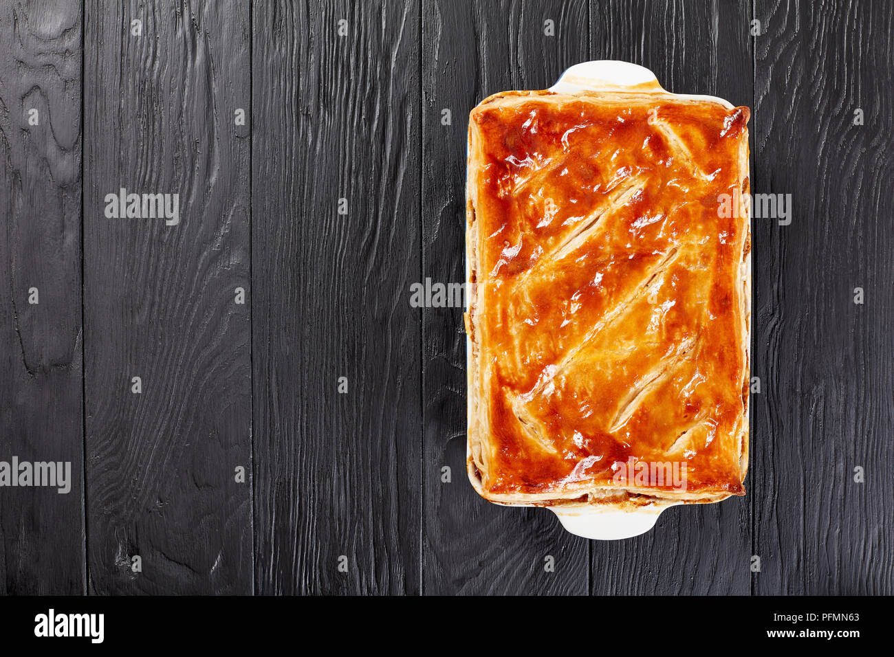 Deliziose Carni bovine e torta di Funghi Conditi con crosta dorata sfoglia di pasta sfoglia in una teglia sul tavolo di legno, ricetta australiana, vista da sopra Foto Stock