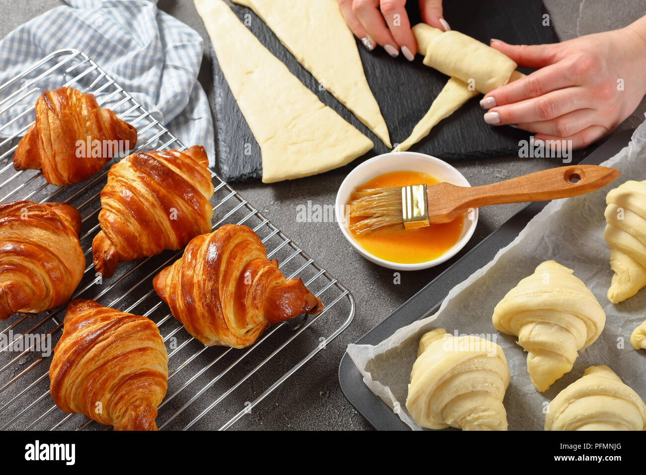La donna è la sagomatura a strati di lievito di pasta lievitata in crescent rotoli per cuocere il croissant francesi. appena sfornato golden brown deliziosi cornetti caldi sono c Foto Stock