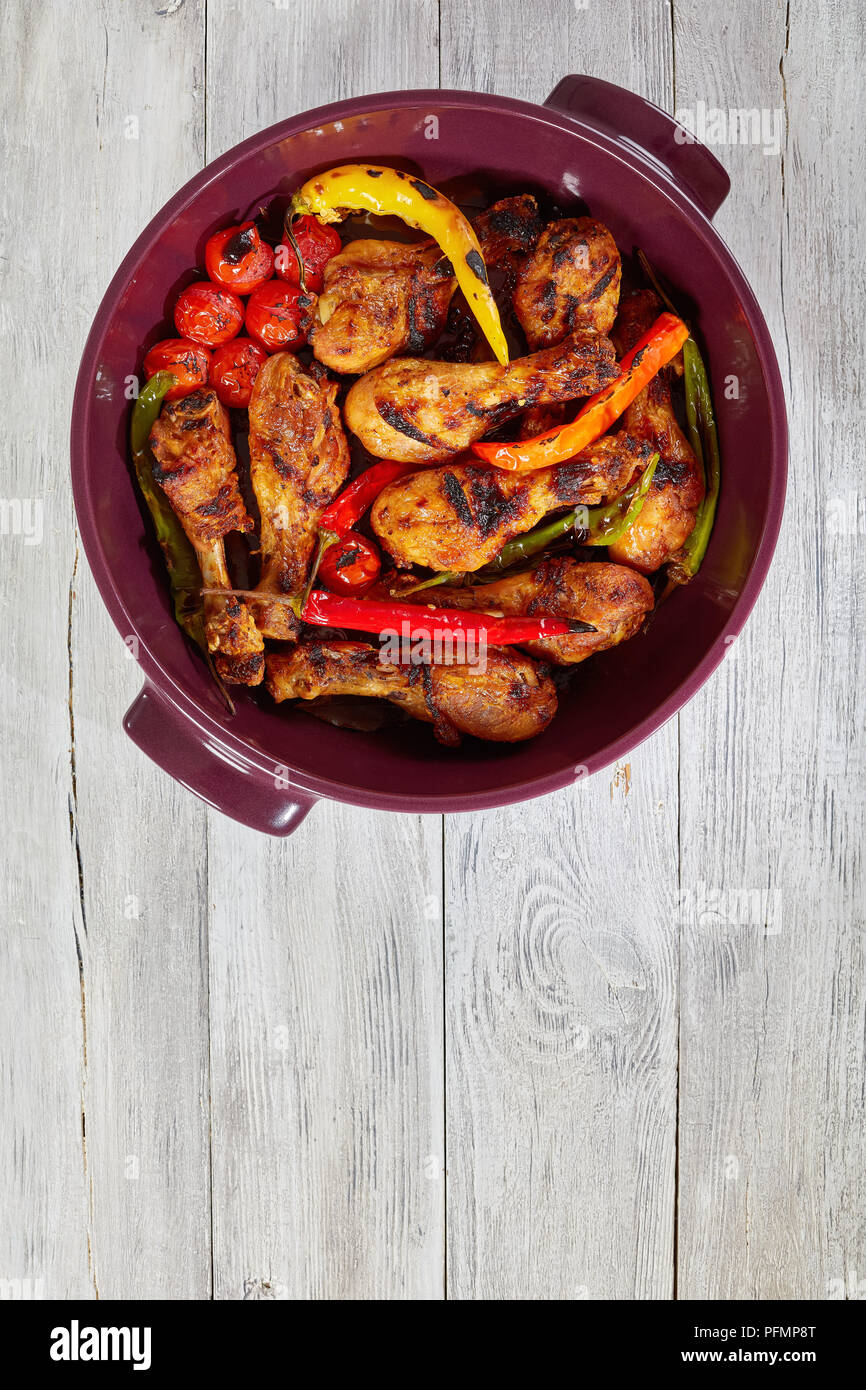 Delizioso pollo Cosce di pollo disossate tostate in forno nel braciere con colorate il peperoncino e i pomodori ciliegia, vista da sopra Foto Stock