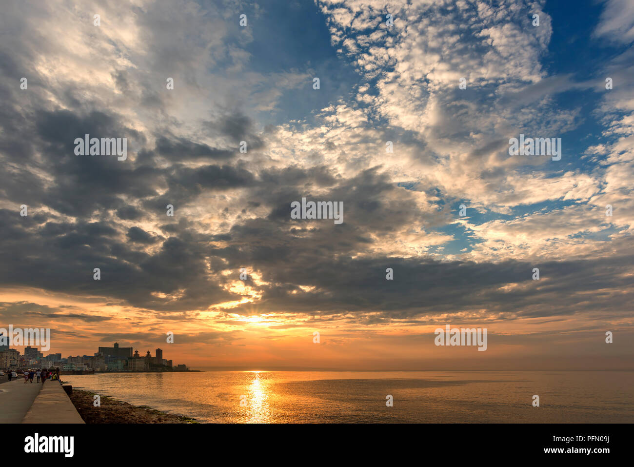 La riflessione del sole le onde dell'oceano, il terrapieno di un antica città con edifici storici, gente camminare lungo il lungomare, il Foto Stock