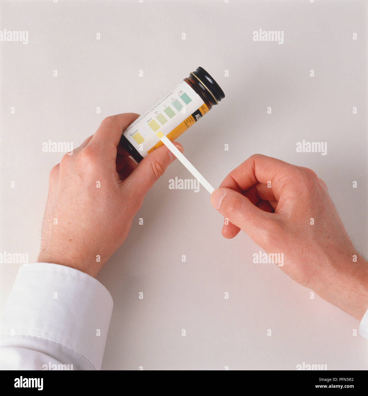 Medico confrontando i risultati di un campione con colori codificati a strisce, vista dall'alto. Foto Stock