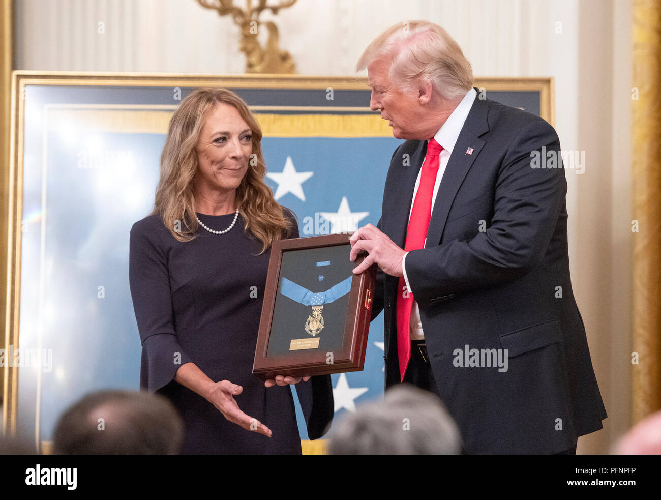 Valerie Nessel, vedova del sergente tecnico John A. Chapman, United States Air Force, sinistra, si erge con il presidente USA Trump, centro, come lei accetta la medaglia d'onore postumo dal Presidente nel corso di una cerimonia che si terrà nella Sala Est della Casa Bianca a Washington DC su Mercoledì, 22 agosto 2018. Il sergente Chapman è stato premiato per le sue azioni il 4 marzo 2002, su Takur Ghar montagna in Afghanistan, dove egli ha dato la sua vita per salvare i suoi compagni di squadra. Credito: Ron Sachs/CNP /MediaPunch Foto Stock