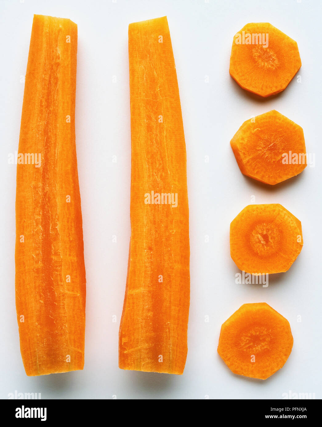 Una carota tagliata a metà per il verso della lunghezza e una fila di fette di carota Foto Stock