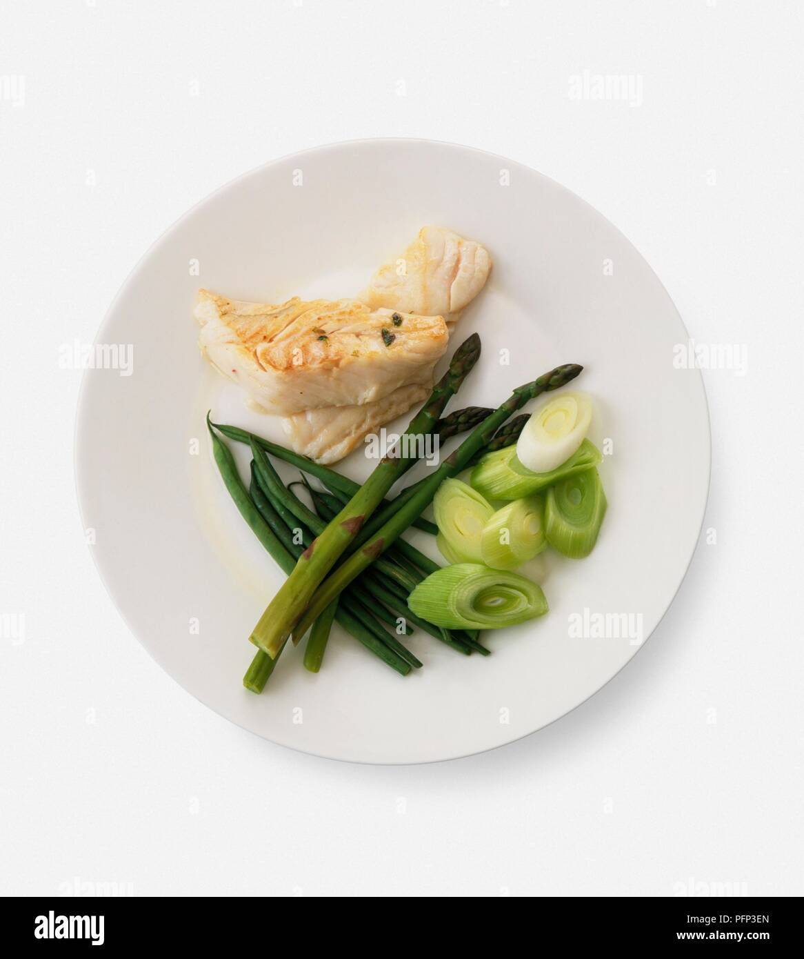 Piccole porzioni di grigliate di pesce bianco e cotto a vapore le punte di asparagi, fagioli verdi e il trito di perdite, servita su una piastra Foto Stock
