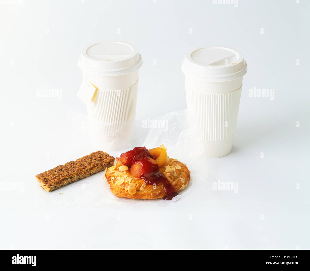 Il tè alle erbe e il caffè in tazze di plastica, granola bar e pasticceria danese Foto Stock