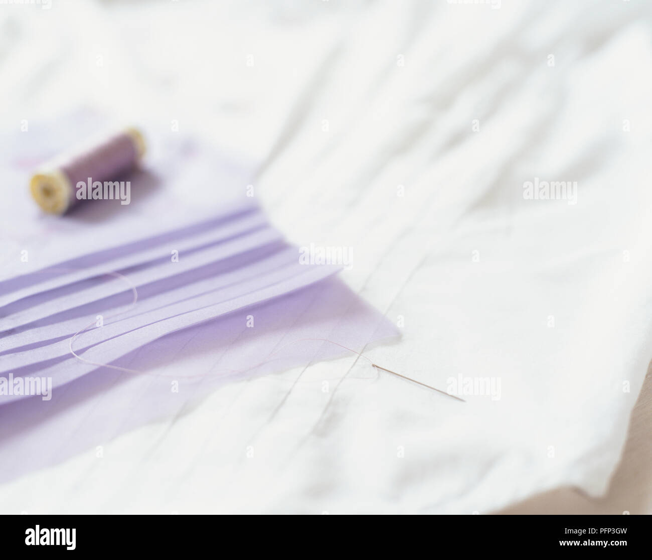 Bianco e lilla a mano tessuti pieghettata, bobina di cotone e ago filettato, close up Foto Stock