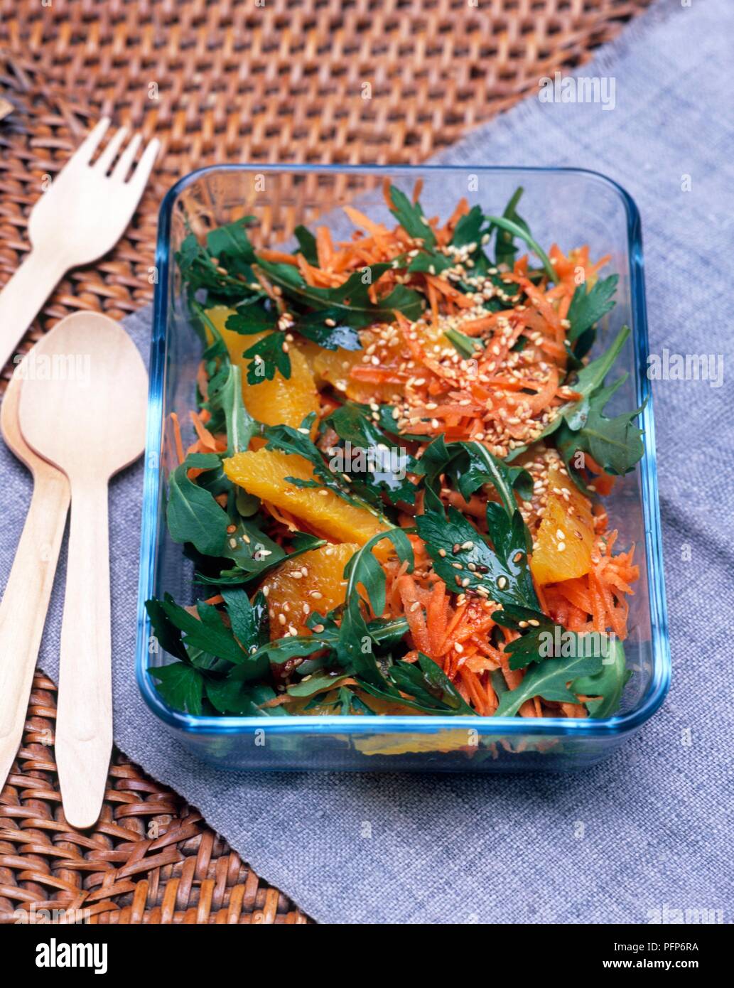 Razzo marocchino, carota e l'insalata di arance con la paprika medicazione e i semi di sesamo, in capsula di vetro, posate in legno nelle vicinanze Foto Stock