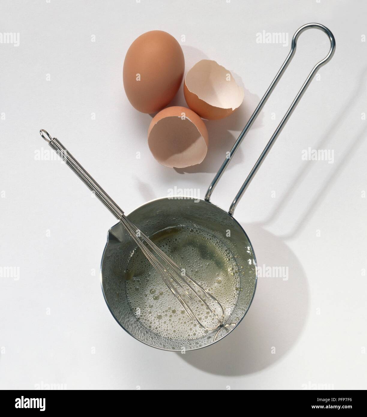 Pentola, frusta, uova e gusci delle uova Foto Stock