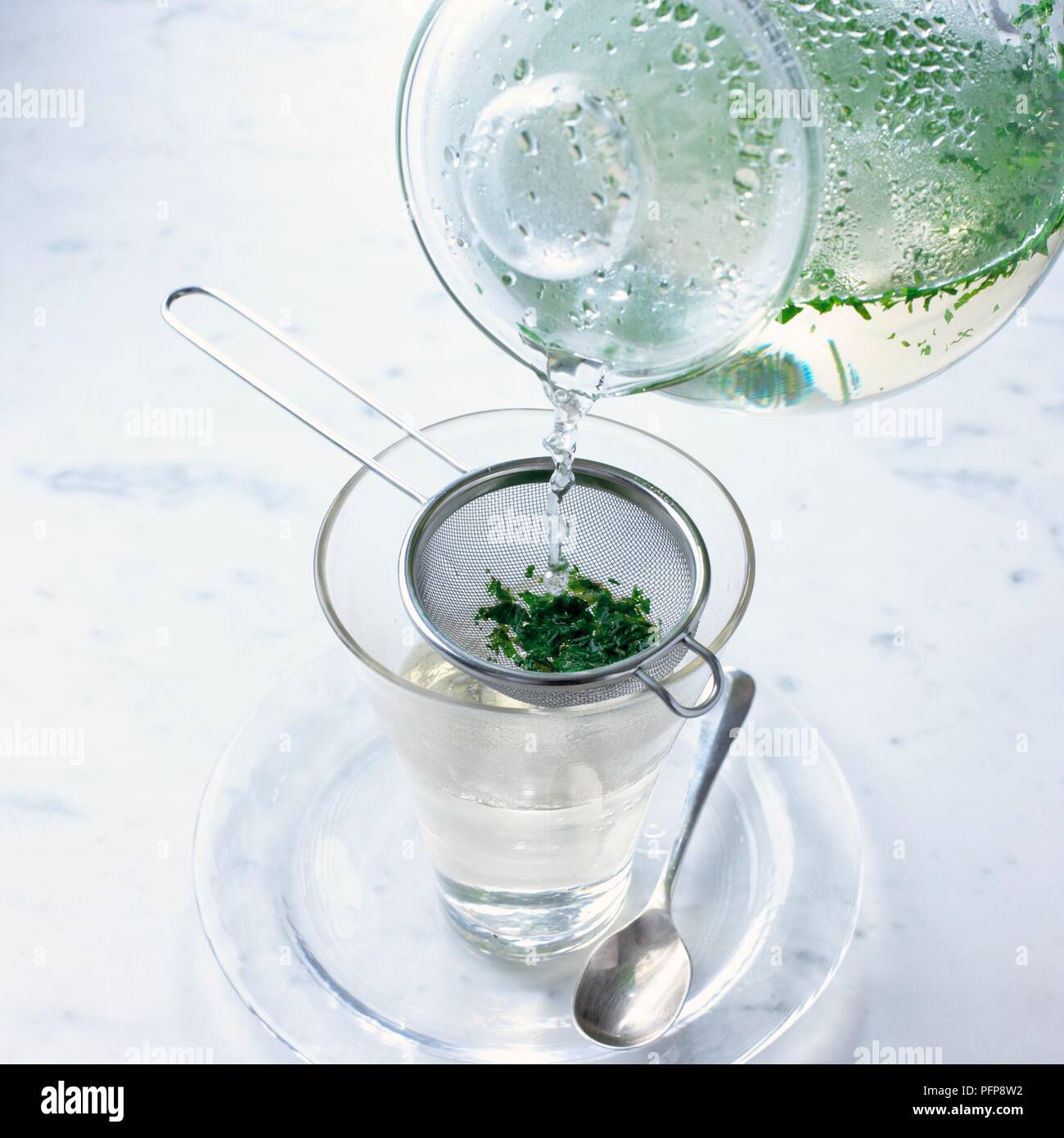 Versando il tè alle erbe da teiera in vetro attraverso la succhieruola, close-up Foto Stock