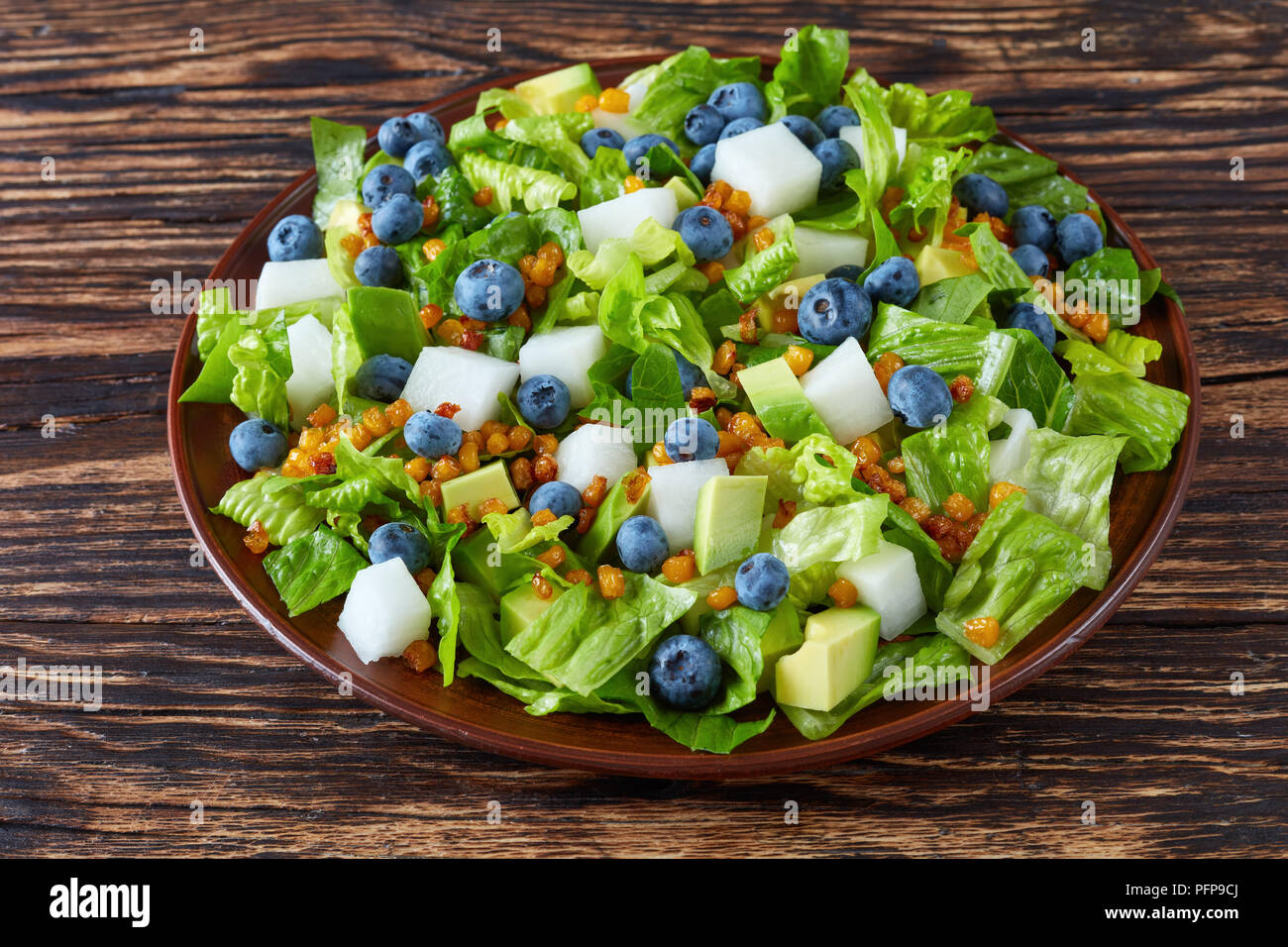 Insalata Messicana Con Mirtilli Romaine Foglie Di Lattuga Jicama Tostati Chicchi Di Mais E Avocado Su Una Piastra Di Argilla Su Una Vecchia Tavola In Legno Rustico Visualizzare F Foto Stock