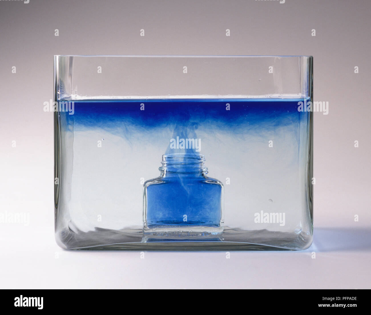 Inchiostro blu in aumento di superficie di acqua nel serbatoio in vetro Foto Stock