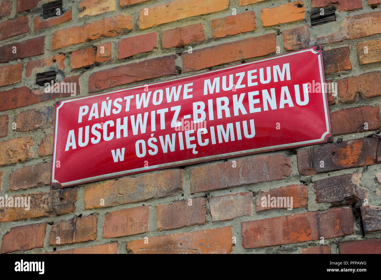 Rosso la piastra metallica del museo di stato vicino all'ingresso del polacco del campo di concentramento nazista di Auschwitz Birkenau Foto Stock