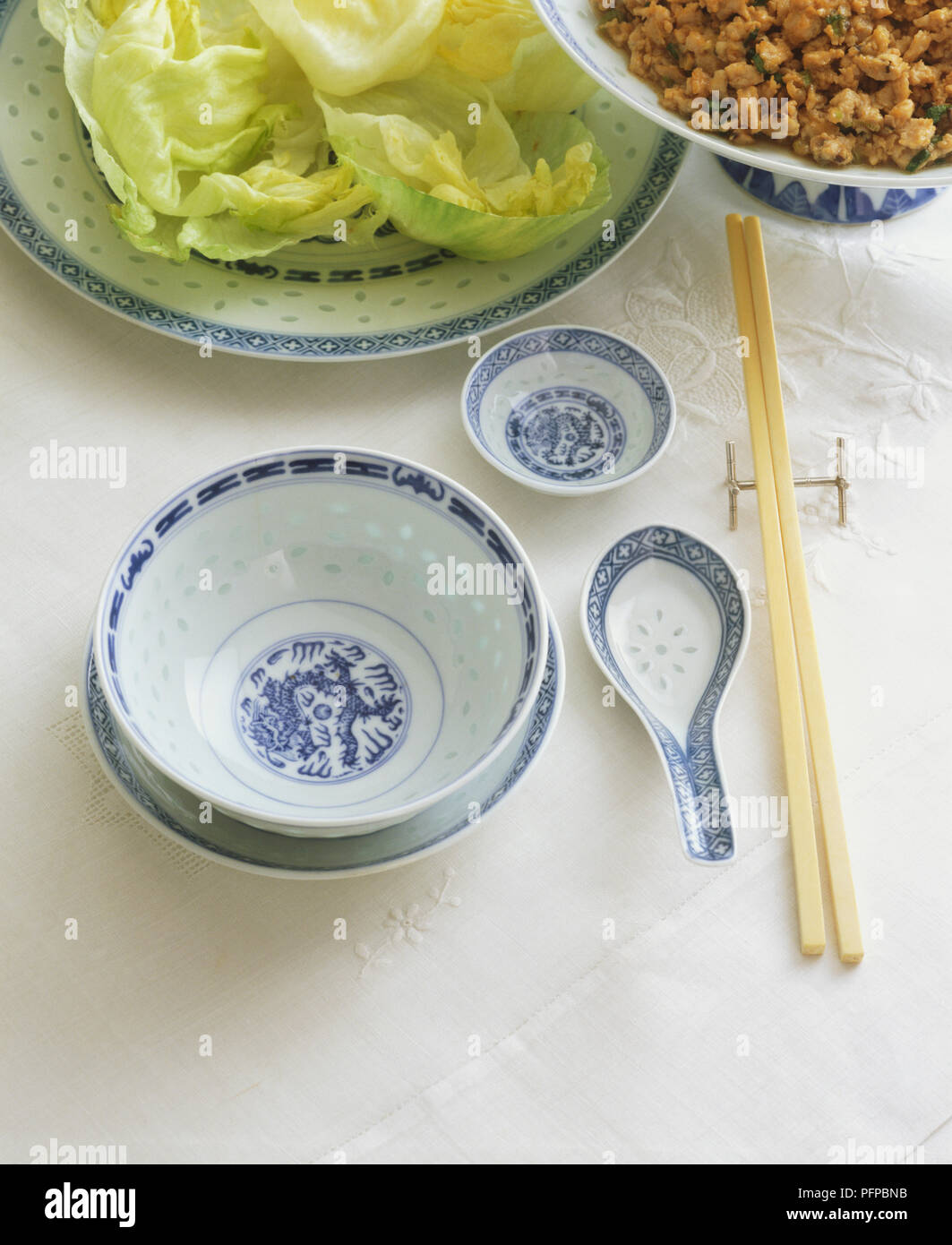 Tabella cinese impostazione con ciotola di riso, cucchiaio, piattino e bacchette. Foto Stock