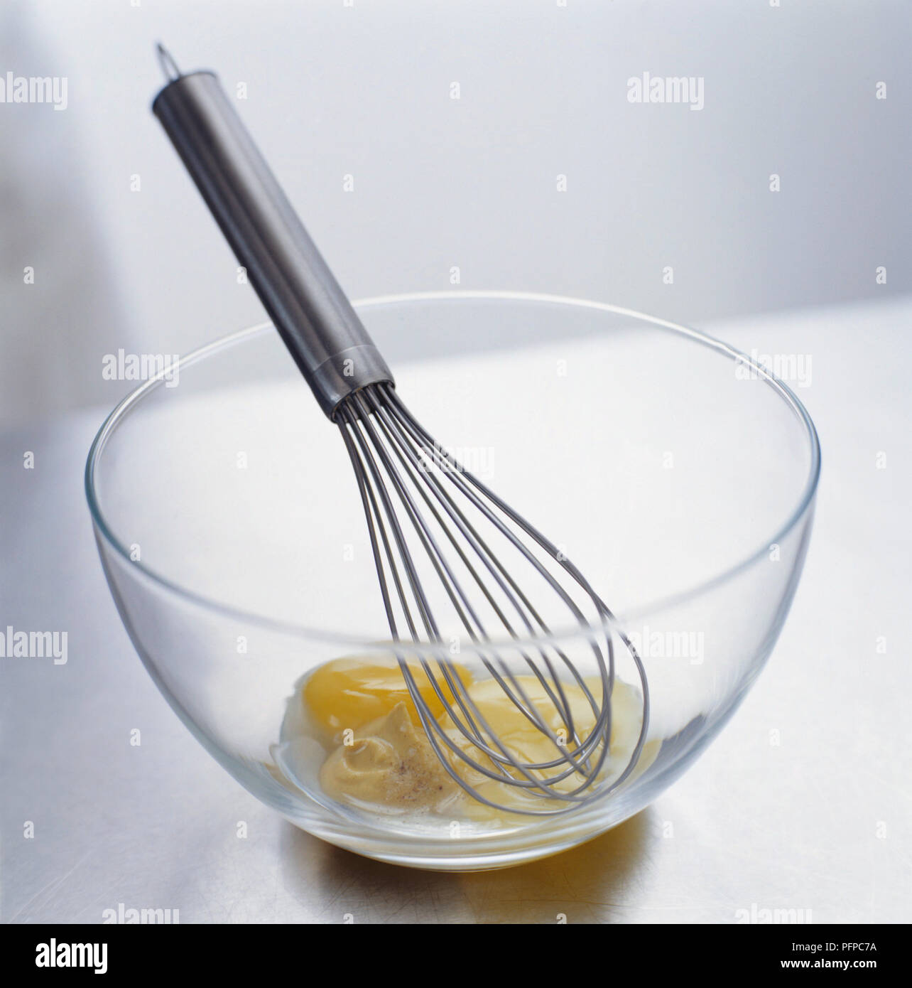 Tuorli di uova, senape e aceto nel recipiente di vetro con frusta, close-up Foto Stock