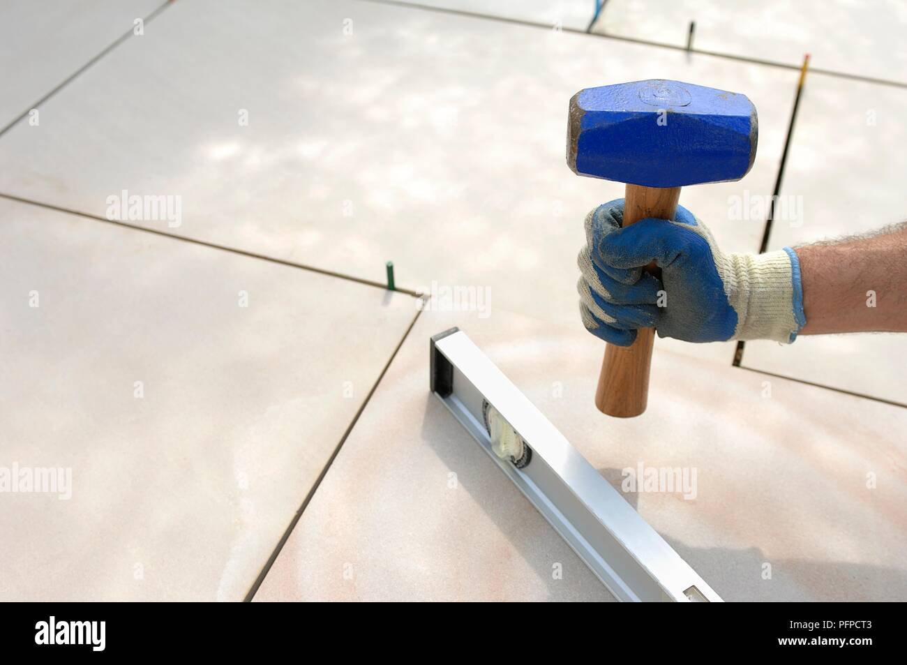 Persona timbratura giù sul cemento con il manico di un martello club, close-up Foto Stock