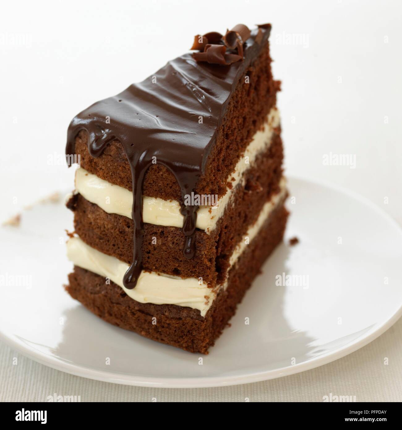 Fetta di cioccolato e crema layer cake sulla piastra bianca Foto Stock