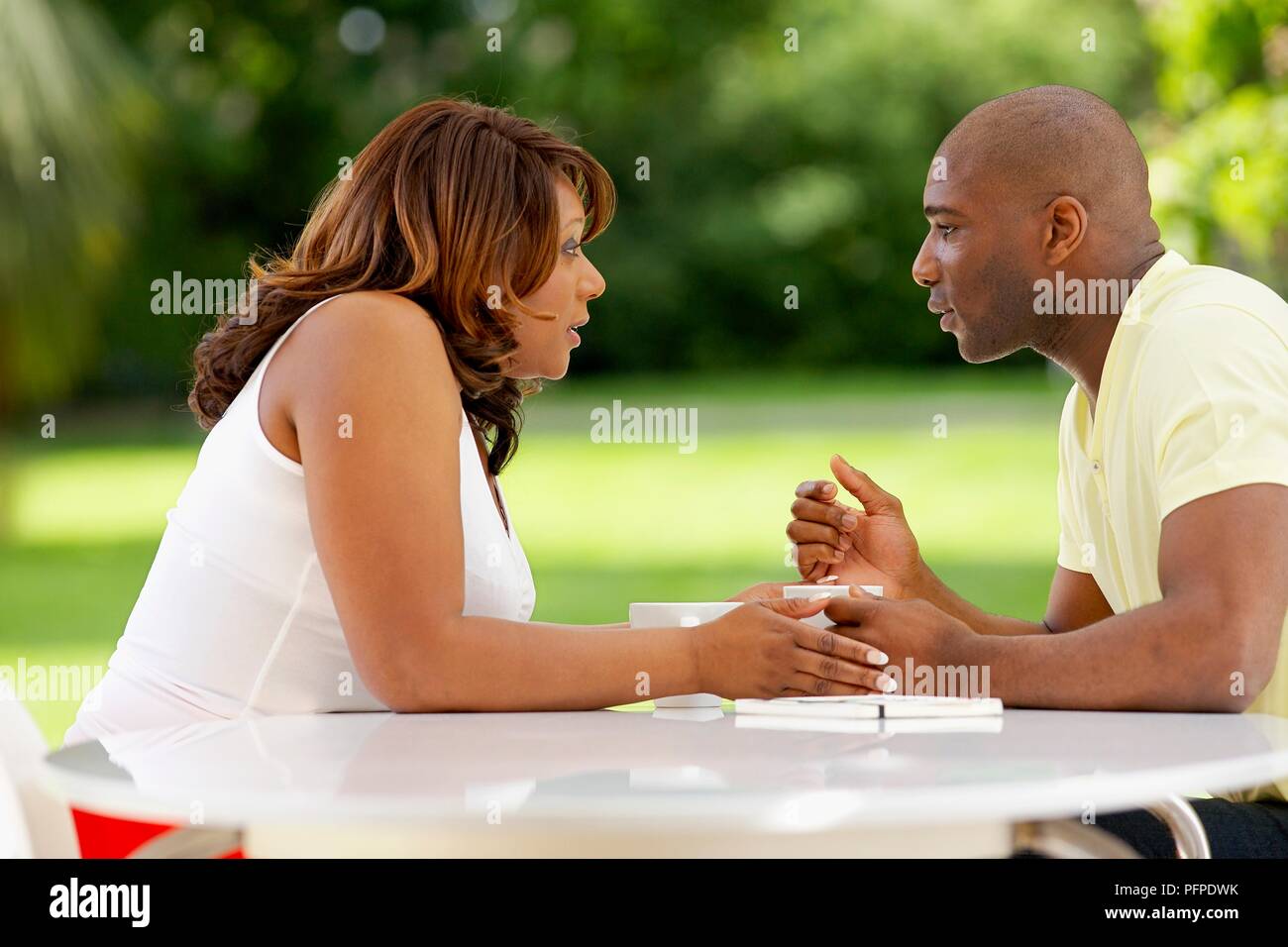 Giovane seduto al tavolo esterno, parlando Foto Stock