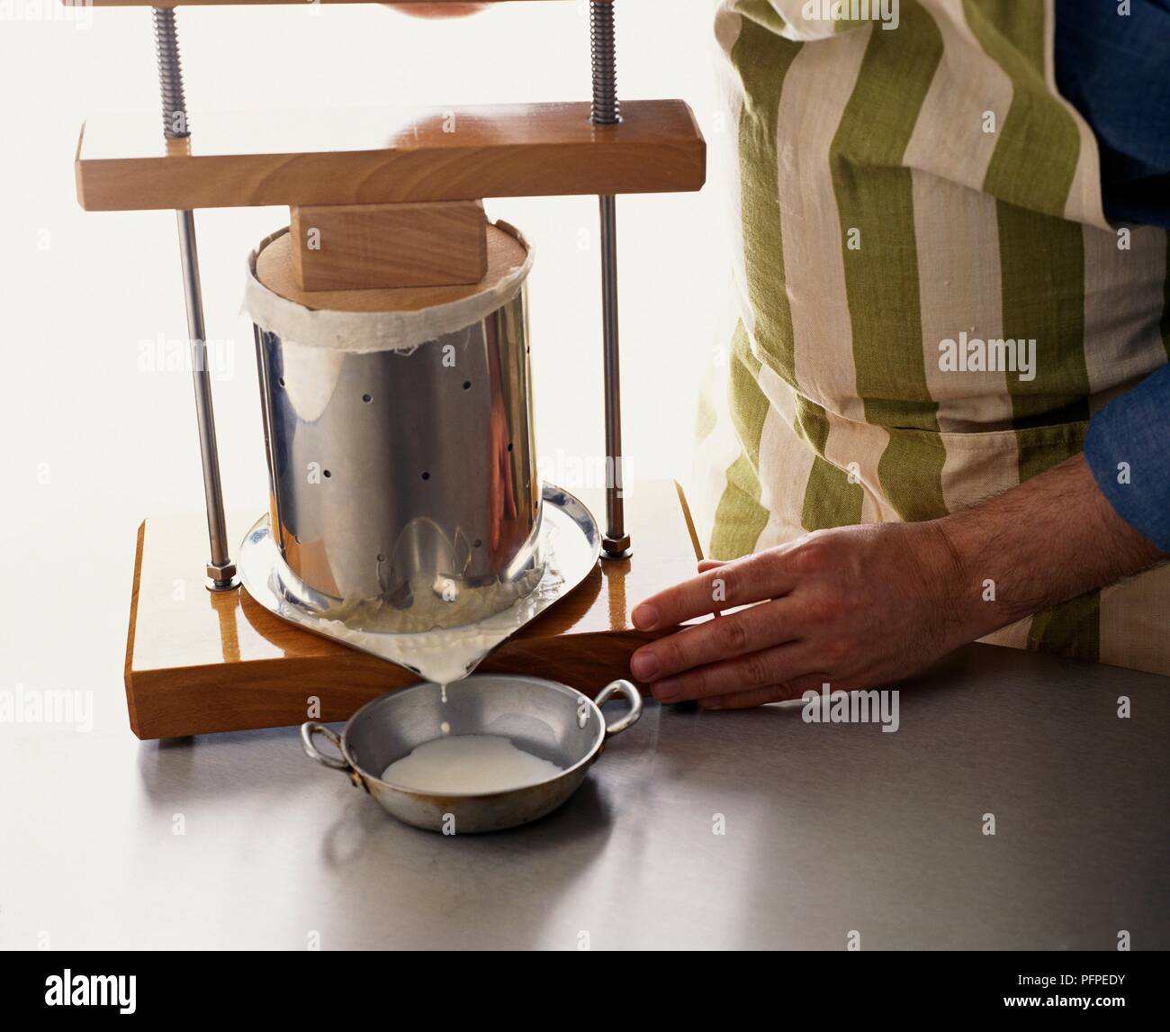 Blocco di spinta sui latticini per rendere al formaggio a pasta morbida che mostra il siero che gocciola fuori alla base della pressa Foto Stock