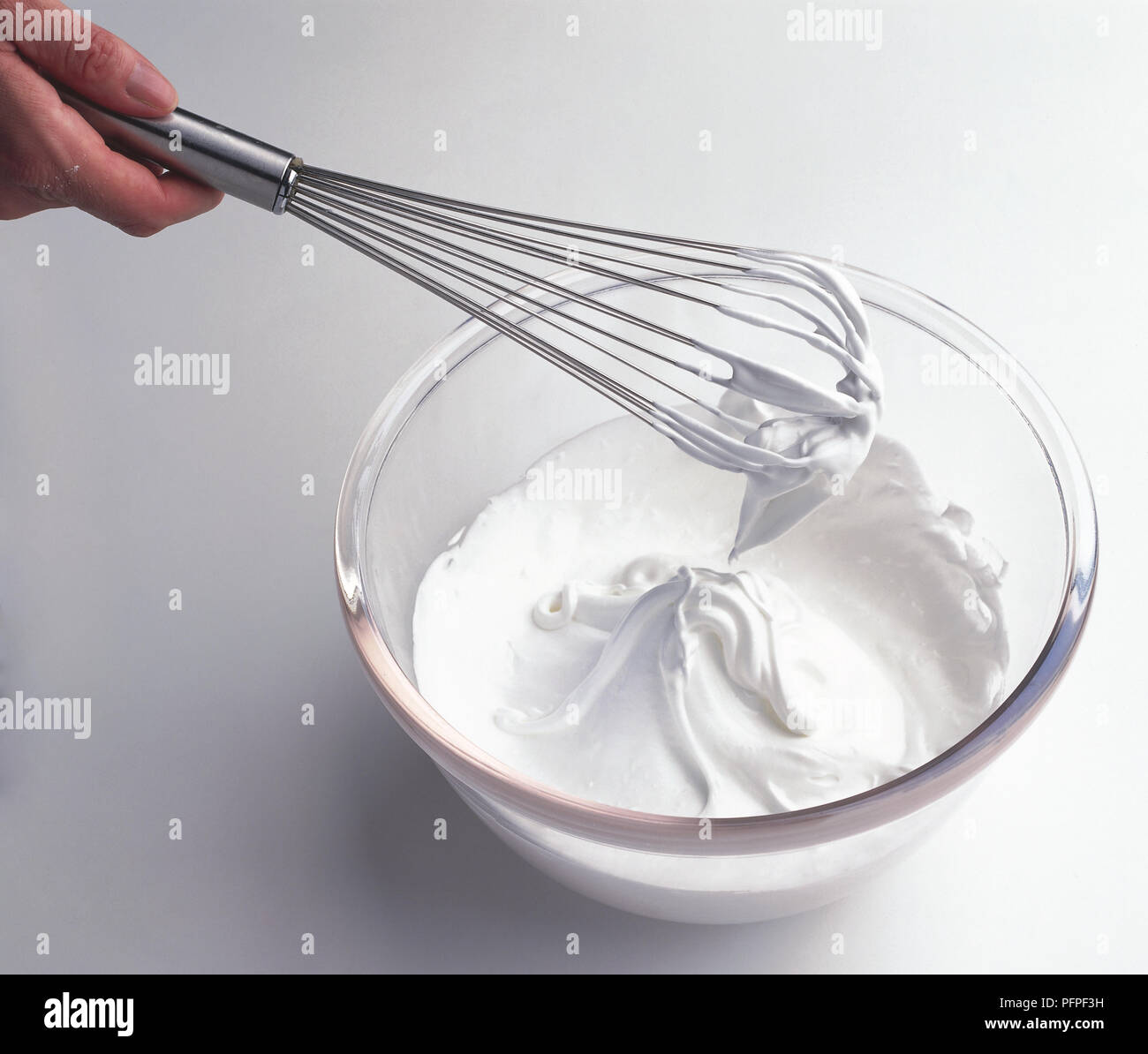 Impasto di meringa su una frusta in recipiente di vetro, close-up Foto Stock