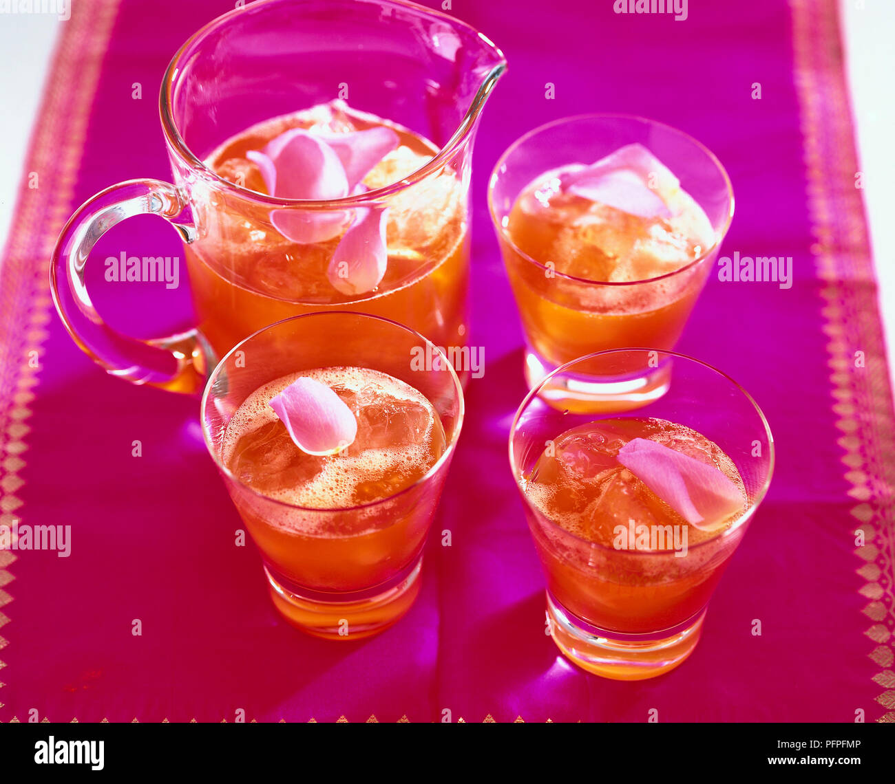 Iced chai tè con petali di rosa in una caraffa e tre bicchieri Foto Stock