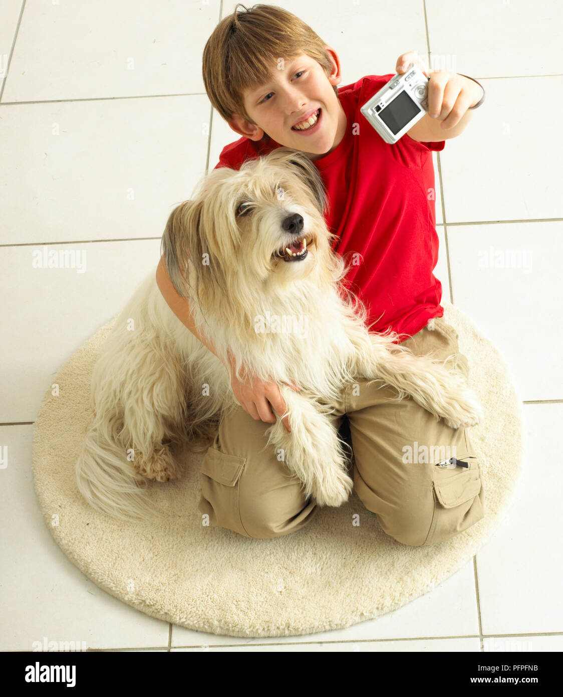 Boy utilizzando una fotocamera per scattare una foto di se stesso e di un cane Foto Stock