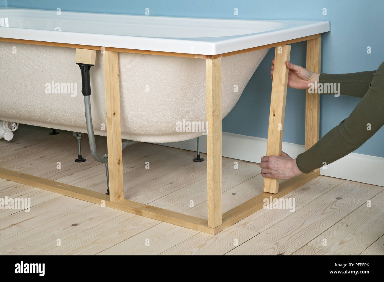 L'uomo mettendo a listelli di legno nella cornice che circonda il bagno Foto Stock