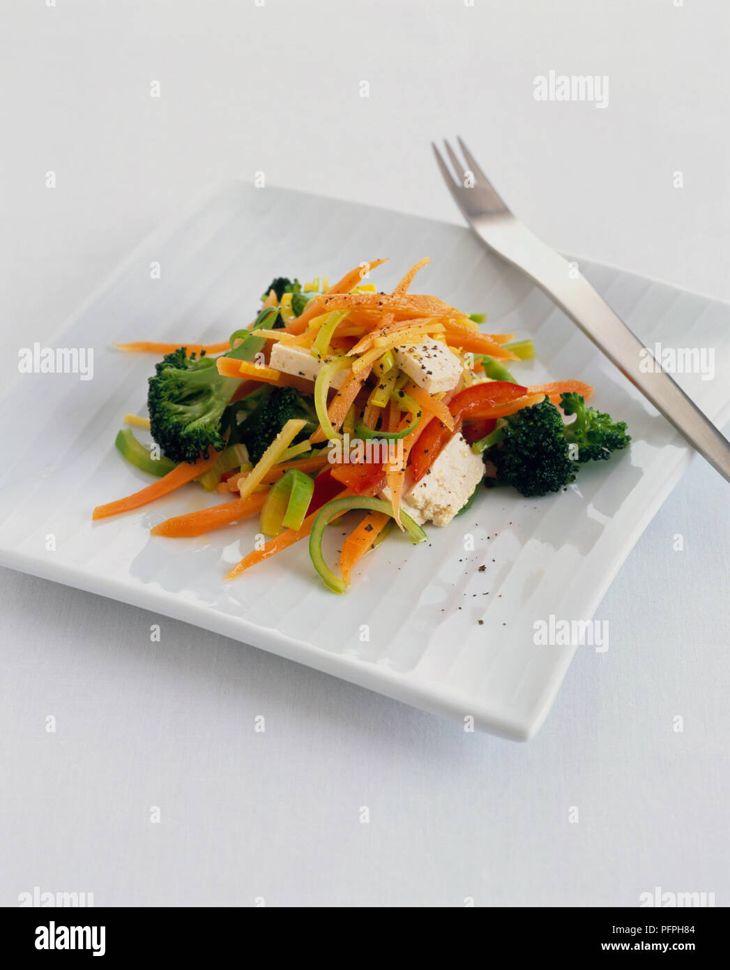 Broccoli, peperoni, la carota e il formaggio feta insalata sul quadrato bianco con piastra forcella Foto Stock