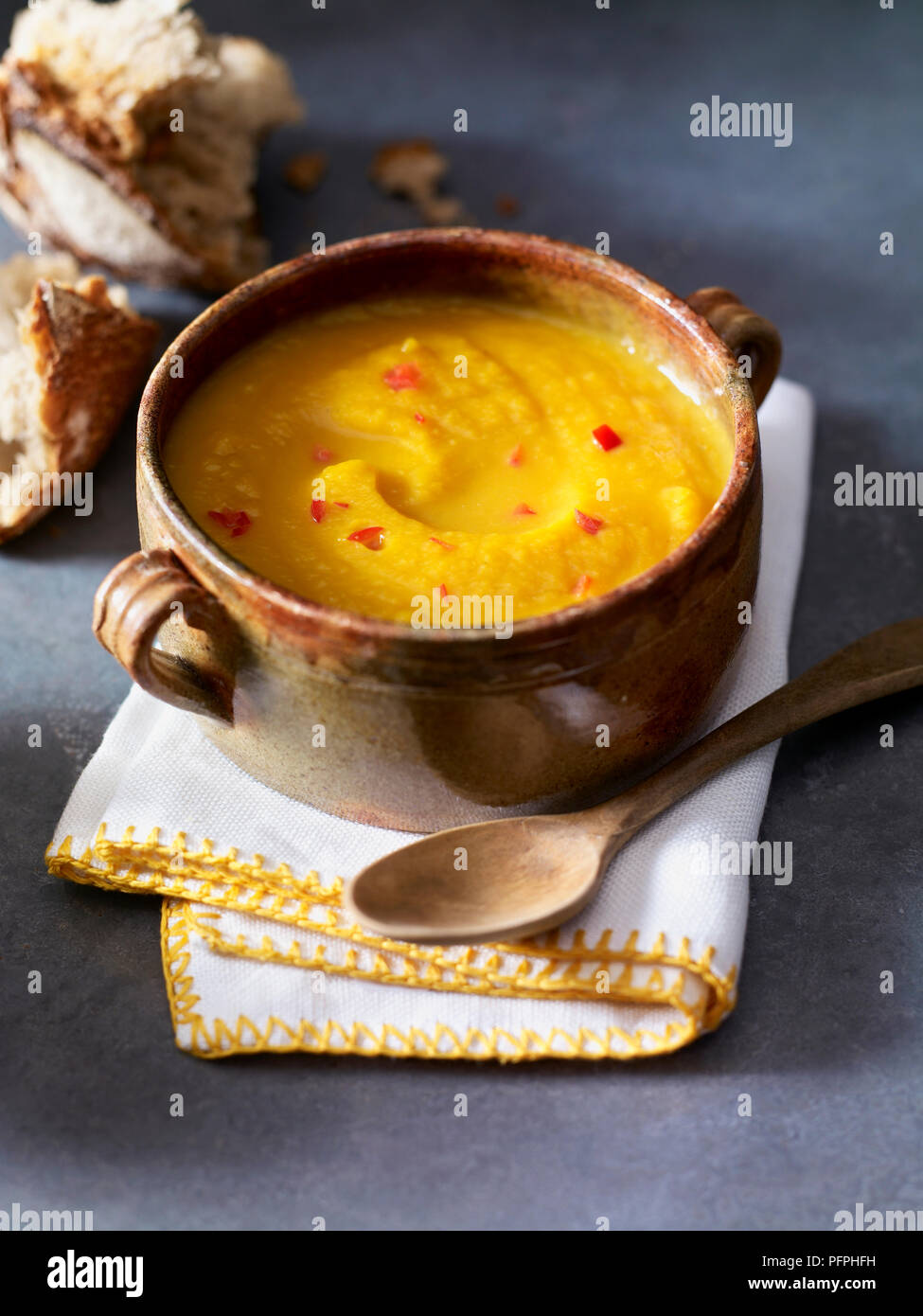 Zucca e zenzero zuppa con il cucchiaio di legno sul tovagliolo piegato sul tavolo, close-up Foto Stock