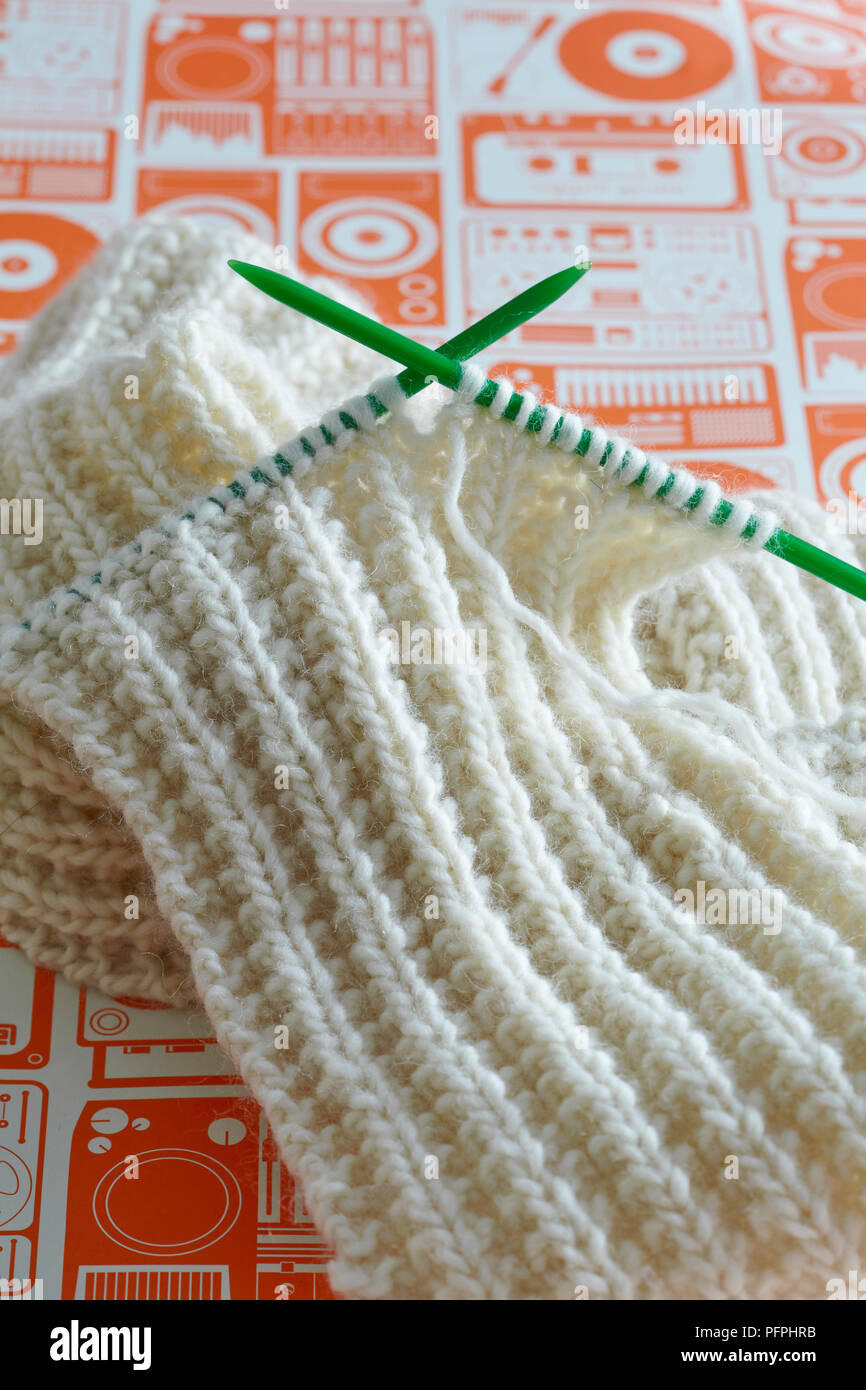 Maglia costola bianca maglia Sciarpa con plastica verde degli aghi di tessitura, close-up Foto Stock