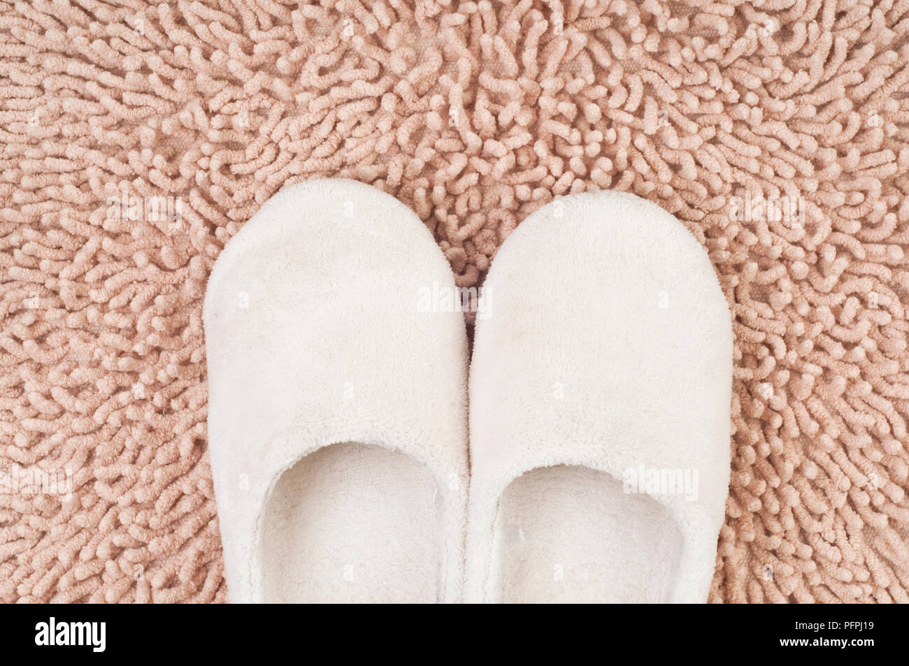 Coppia di soft bianca Pantofole da bambino sul beige shag velluto, vista aerea Foto Stock