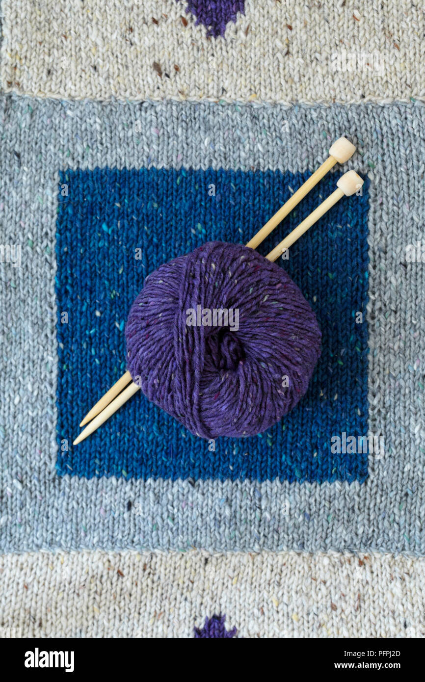 Coperta di maglia (tarsie tecnica) con cuciture cucite con materasso stitch, sfera di lana di colore viola e degli aghi di tessitura Foto Stock