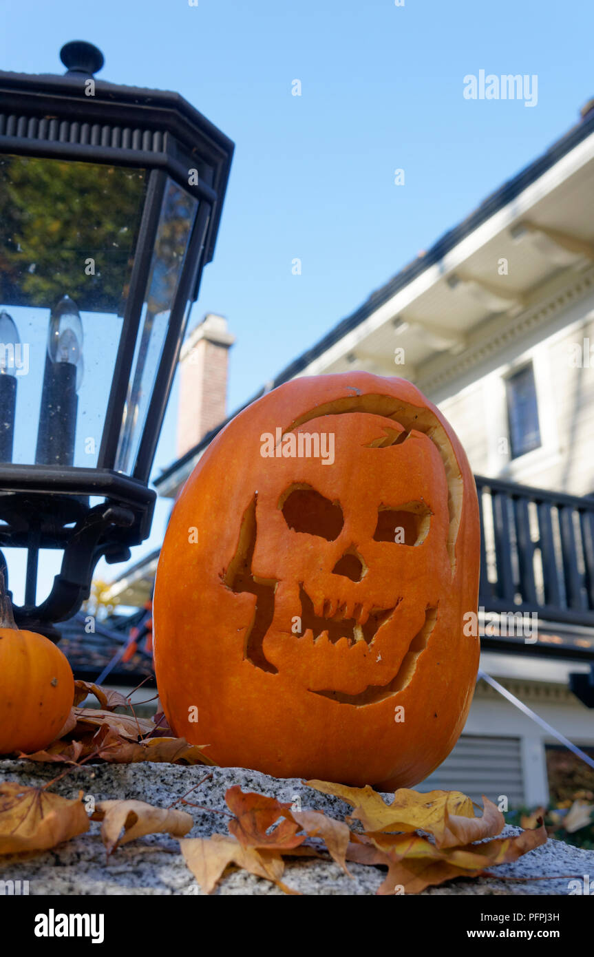 Un scolpito zucca di Halloween o jack-o-lantern su un muro di pietra di fronte a una casa Foto Stock