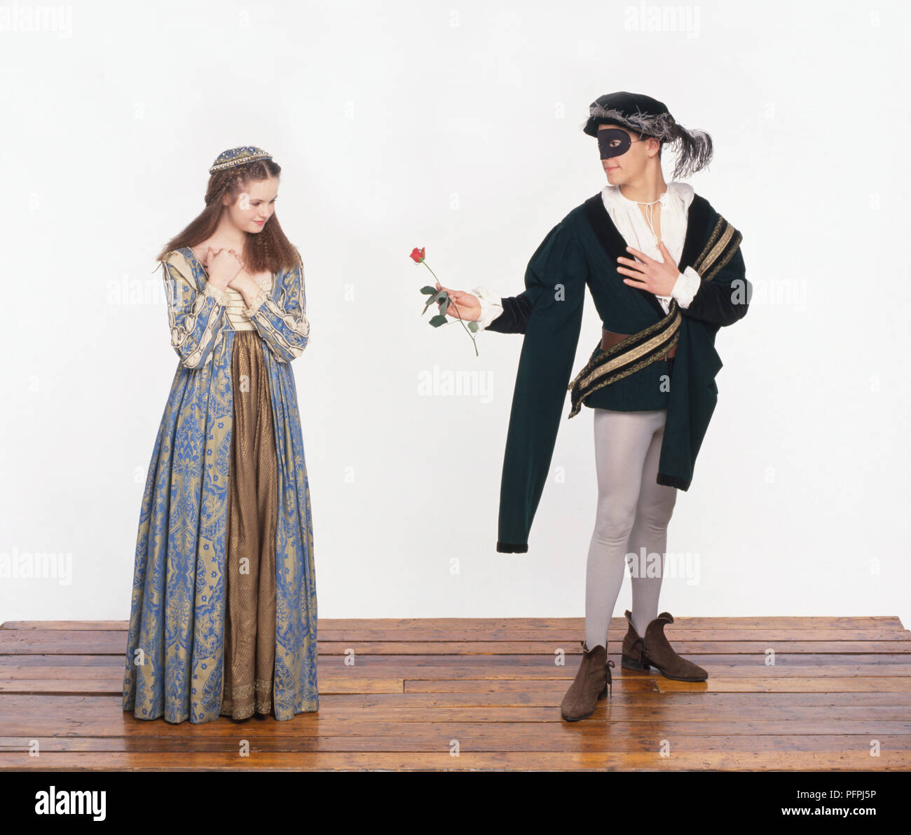 L uomo e la donna che indossa il xvi shakespeare-era costume, uomo consegna rose a donna, vista frontale Foto Stock
