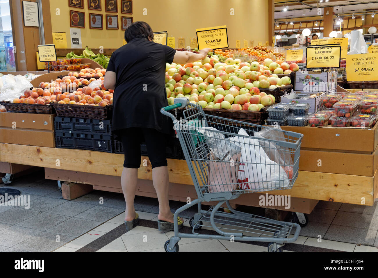 Donna canadese cinese che acquista frutta fresca in un mercato di prodotti Foto Stock