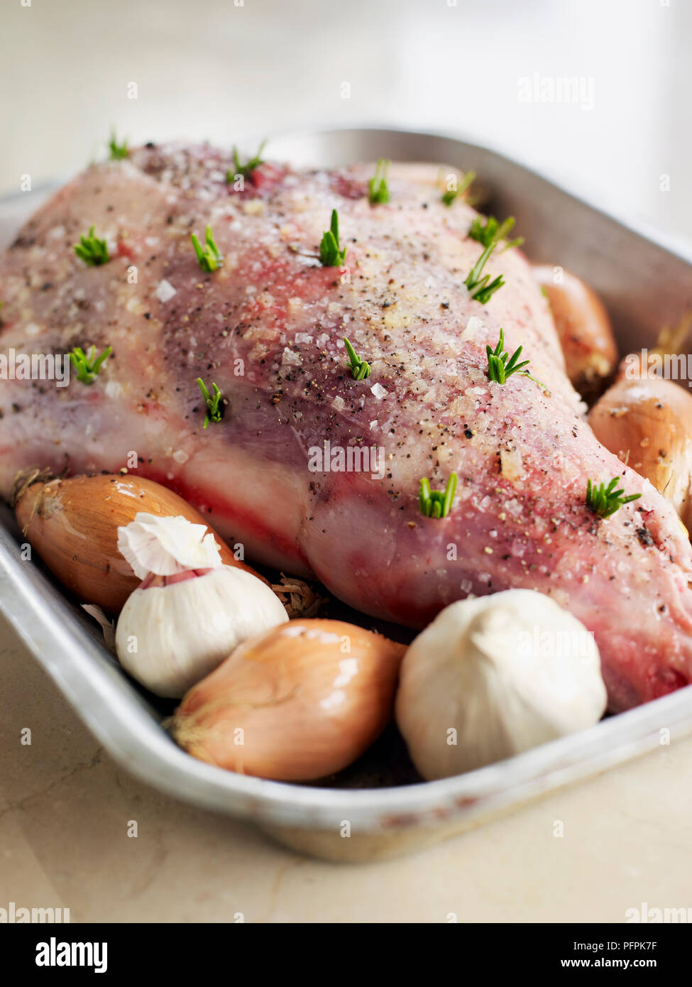 La gamba di agnello costellata di rosmarino, in teglia, close-up Foto Stock