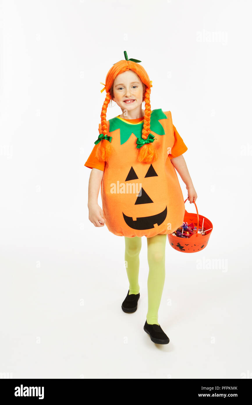 Ragazza vestita come una zucca con un trucco-o-trattare la benna Foto Stock