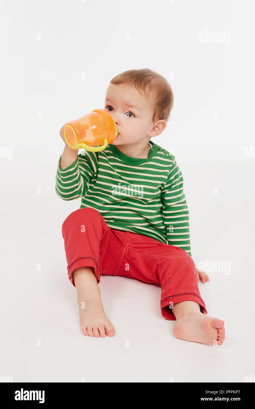 Little Boy in verde stripey top bere dal bicchiere (Modello età - 22 mesi) Foto Stock