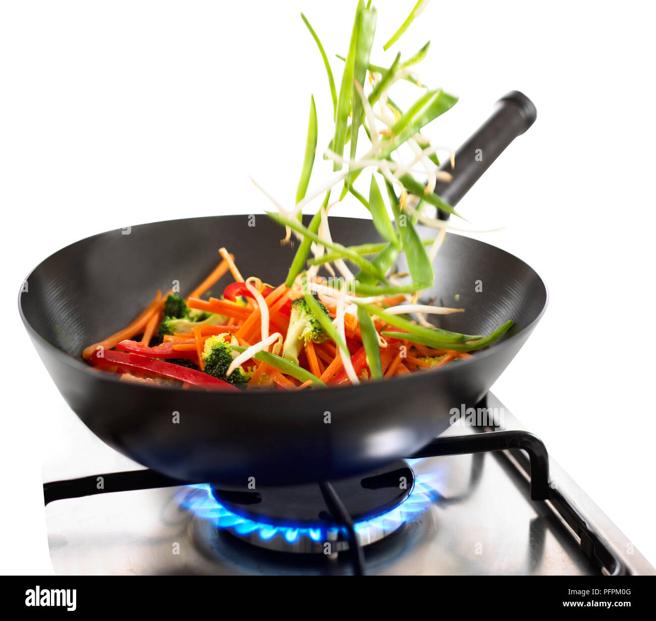 Verdure essendo scagliata nel wok sul fornello a gas, close-up Foto Stock
