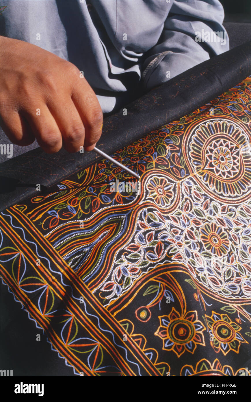 India, Gujarat, nr Bhuj, Niruna, man praticando craft di Rogan, tessuto decorativo con intricati, laccato goffrato-dei modelli di lavoro, vicino. Foto Stock