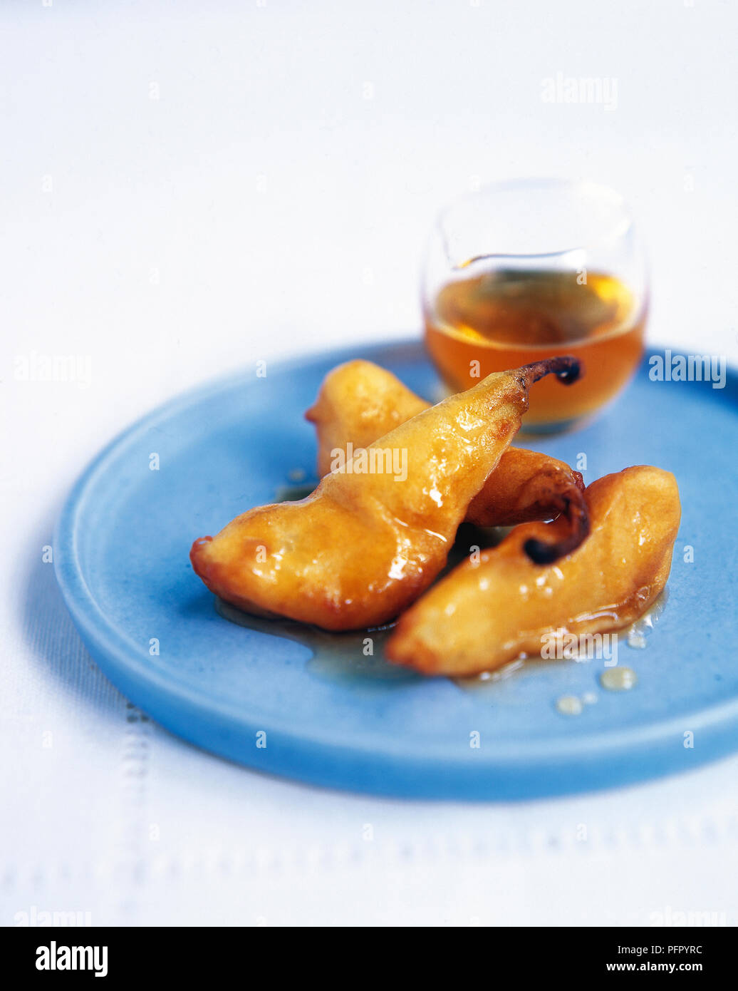 Iraniane di fritte Frittelle di pera con cannella sciroppo di miele in piccola brocca sulla piastra blu Foto Stock