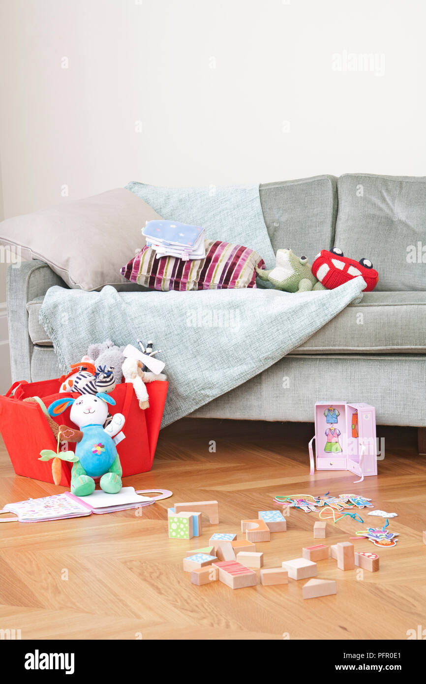 I giocattoli sul divano e sul pavimento in legno Foto Stock
