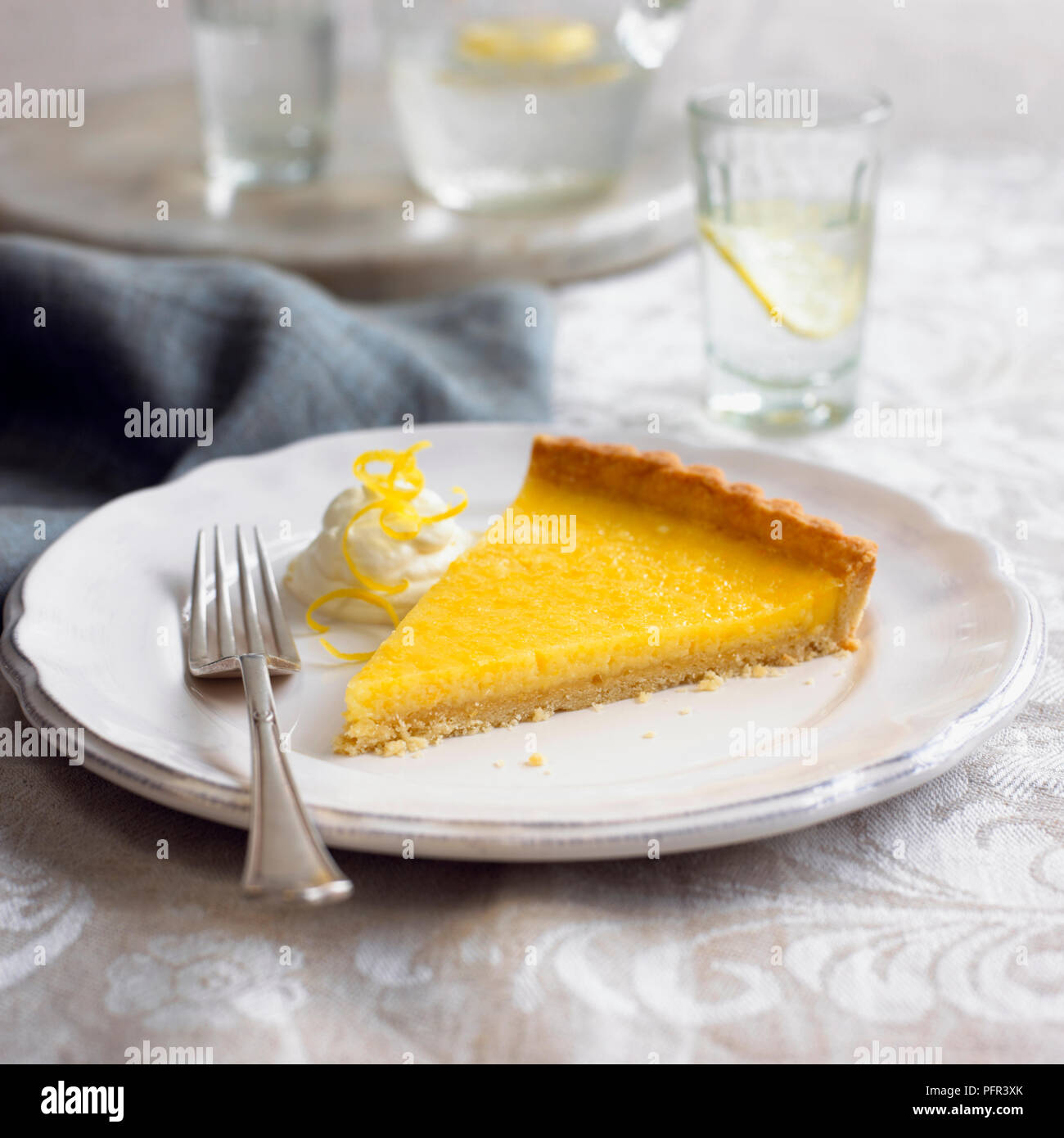 Tarte Au Citron, Francese crostata al limone con la panna e la scorza di limone, su di una piastra con forca Foto Stock