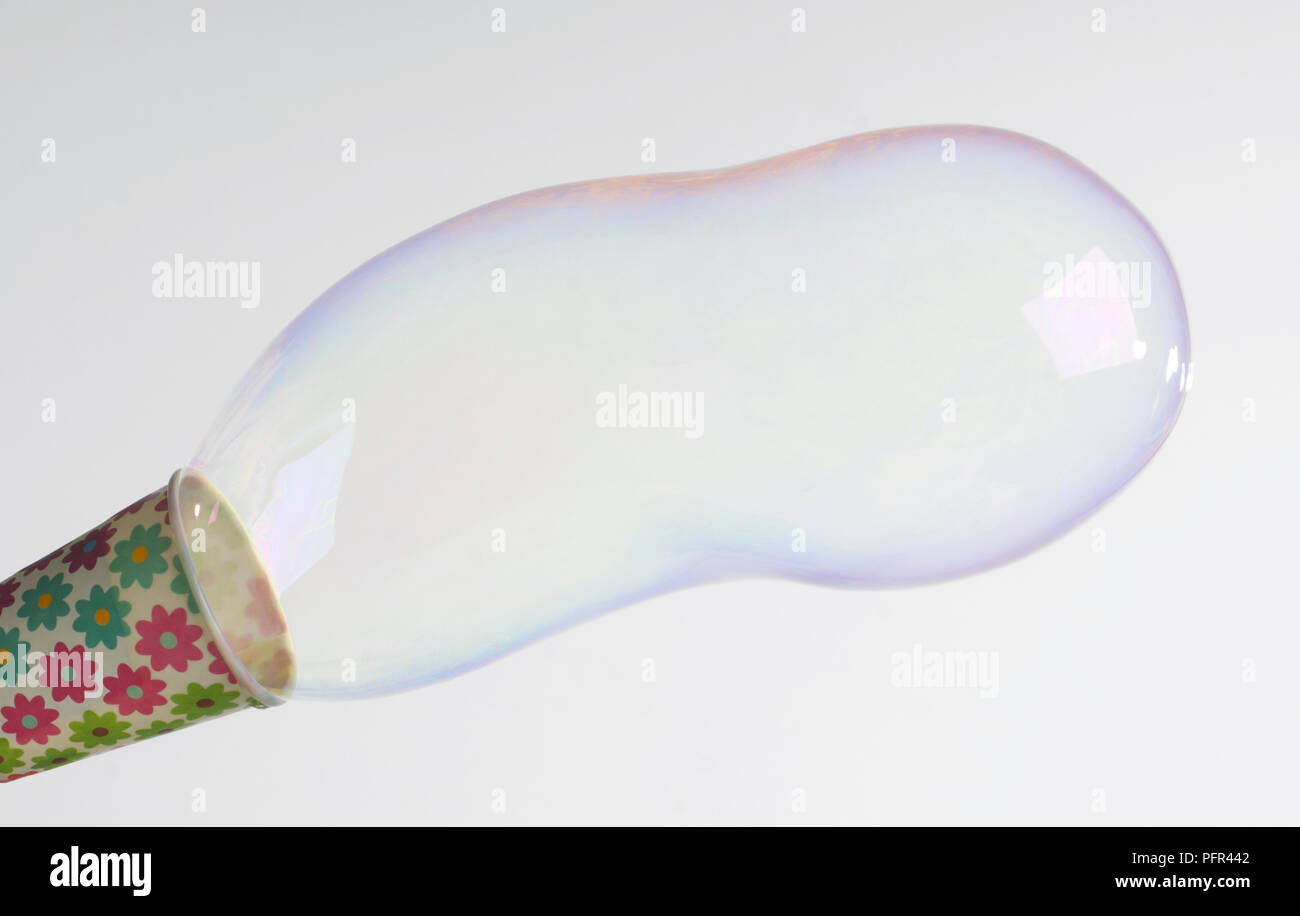 Soffiare bolle attraverso il tubo di carta o coppa, close-up Foto Stock