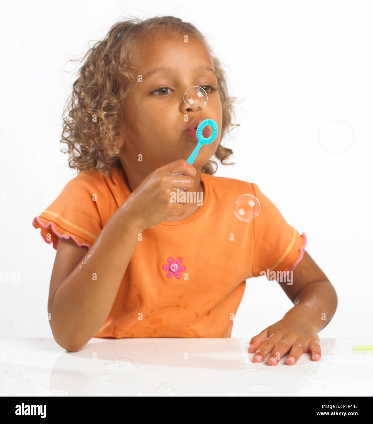 La ragazza (4 anni) soffiare bolle attraverso il bubble wand, 4 anni Foto Stock