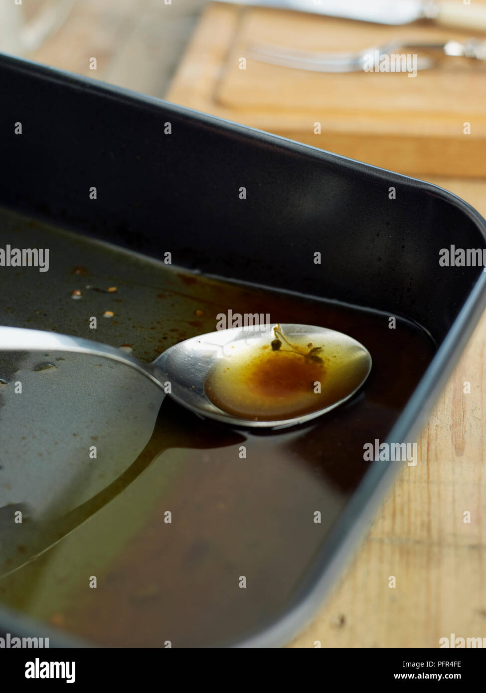 Inclinando la tostatura di stagno e di scrematura fat off inizio dei succhi di frutta, utilizzando un cucchiaio Foto Stock