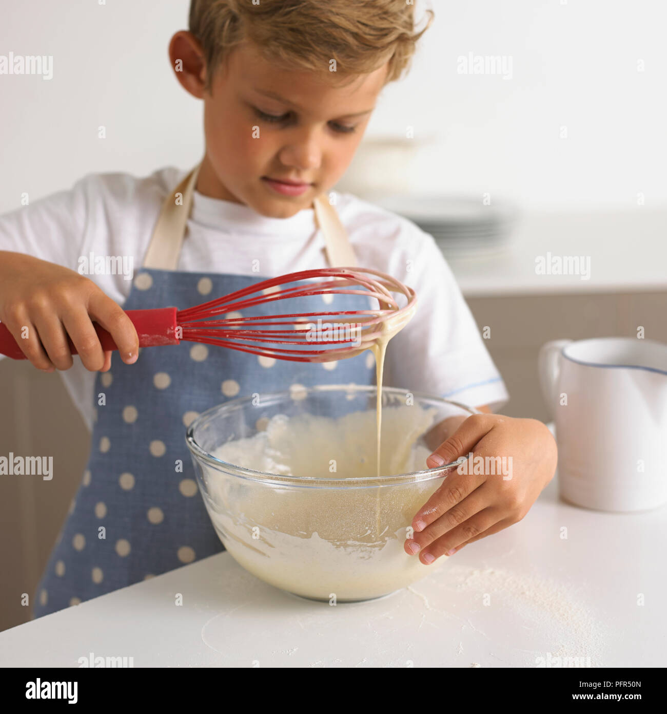 Ragazzo sbattere pastella di frittella dolce in una ciotola, 6 anni Foto Stock