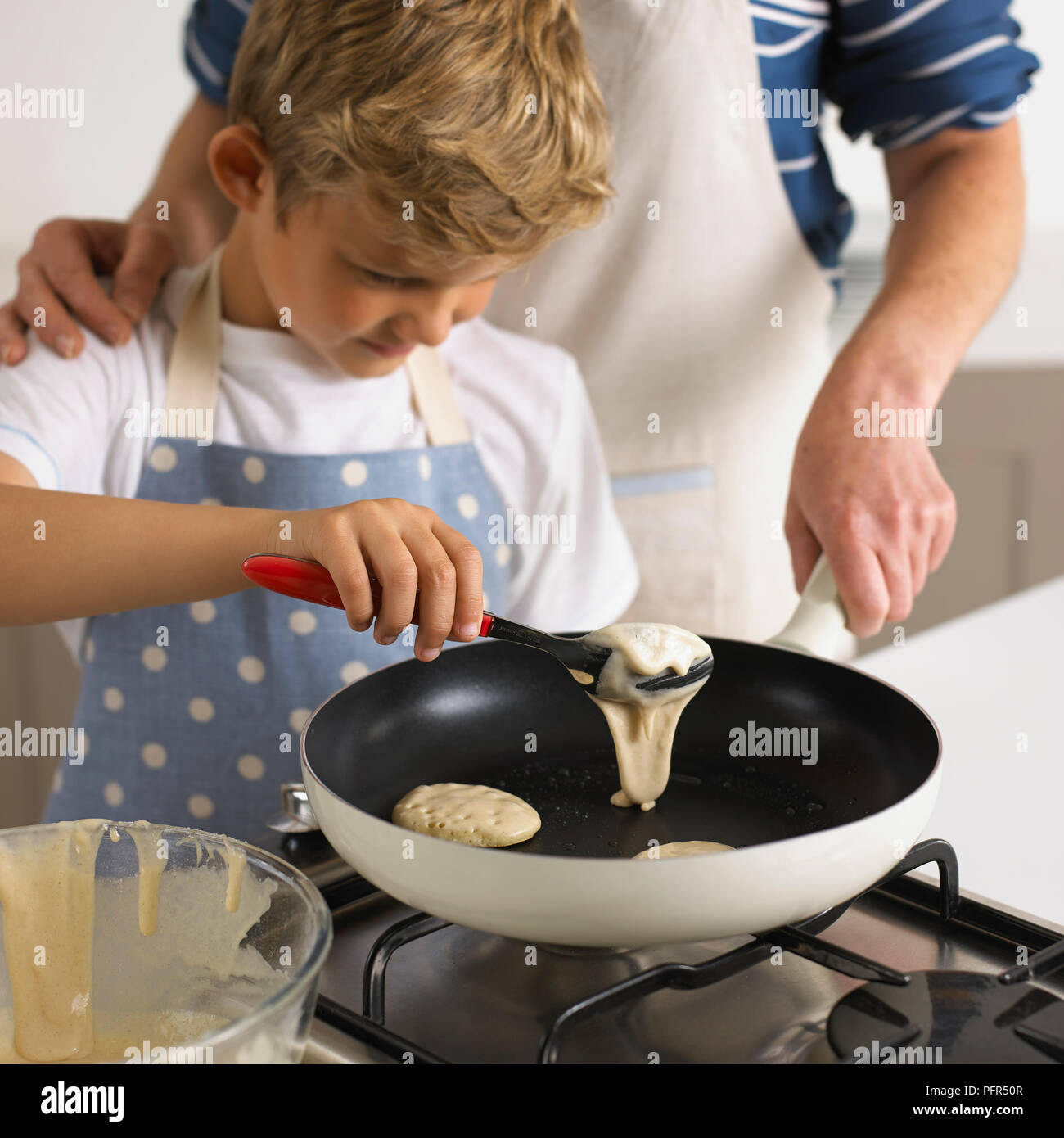 Capovolgimento di frittelle in una padella, 6 anni Foto Stock